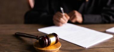 Judge fills out a form on a desk, with a gavel in the foreground