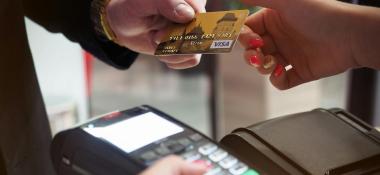 Person hands a credit card to a person holding a handheld scanner